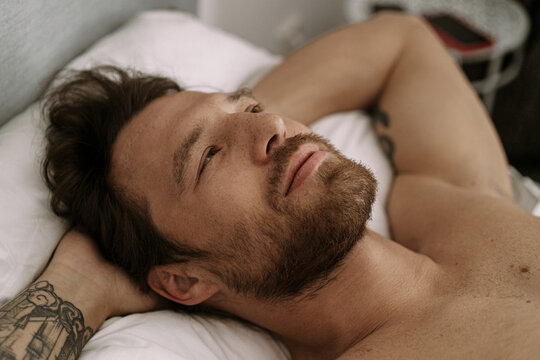 Handsome man in bed after sleep wakes up and starts a new day.