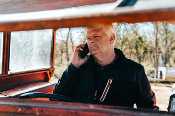 older modern man talking on the phone inside of a tractor