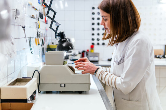 woman filing glass of glasses in the workshop of an optician