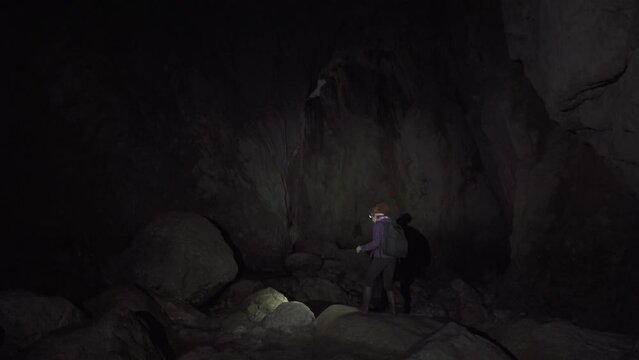 Woman with headlamp and backpack hiking through a cave
