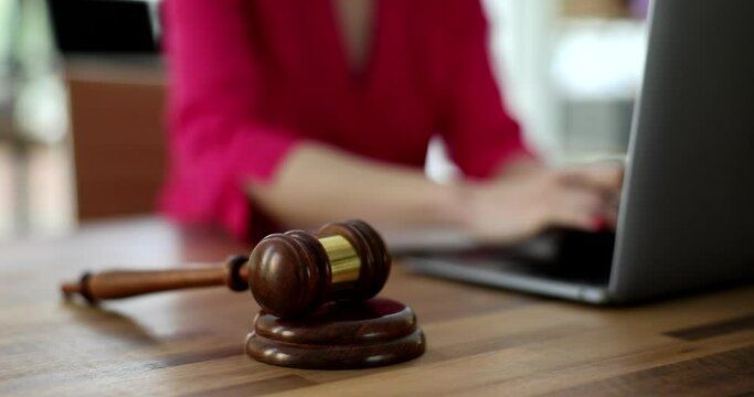 Gavel of judge lying against background of woman behind laptop closeup 4k movie slow motion. Criminal liability for internet fraud concept
