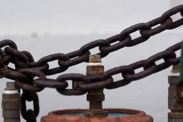 Rusty chains lock a valve system to avoid tampering.