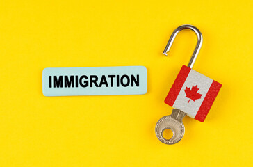 On the yellow surface is an open lock with a key and a sticker with the inscription - immigration