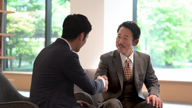 契約成立のイメージ　握手、契約締結、協力など、成功するビジネスシーン　姿のクールなアジア人の男性