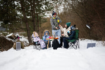 Family with three children in winter forest spending time together on a picnic.