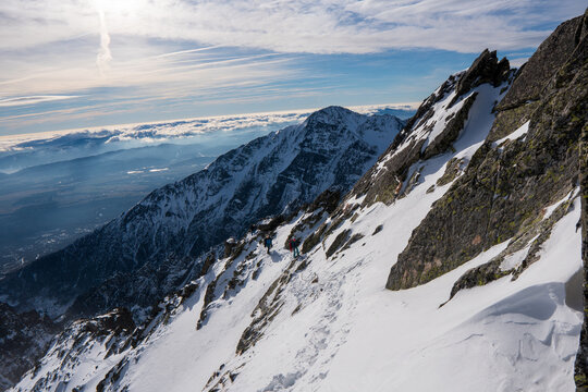 Dramatic, rocky, snowy mountain range, peaks with mist and clouds, High Tatras, Lomnicky Stit, Slovakia, European alps.