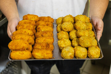 Vassoio di una pizzeria napoletana con crocchè di patate e frittatine di pasta appena fritti e...