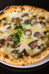 Pizza tradizionale napoletana con mozzarella, salsiccia e basilico fresco servita in una pizzeria