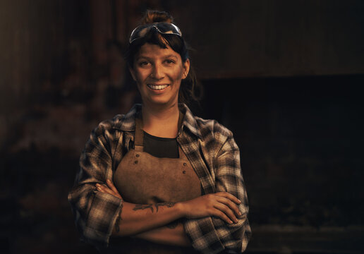 Woman blacksmith, portrait and smile in workshop, industrial warehouse or trade with entrepreneurship. Small business owner, female entrepreneur or confident in factory, industry or metalwork artisan