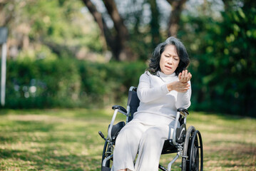 Fototapeta na wymiar Asian old woman sitting on a wheelchair outdoors in the garden There is pain in the heart