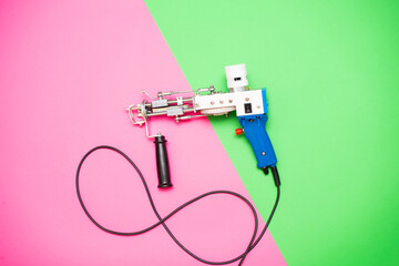 A tufting gun against a bright pinkang green colored background.	 - 605166275