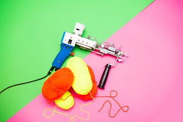 A tufting gun with multicolored yarns against a bright colored background.	