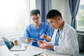 Obraz premium Dentist sitting at table with jaw samples tooth model and working with tablet and laptop in dental office professional dental clinic. medical doctor working.