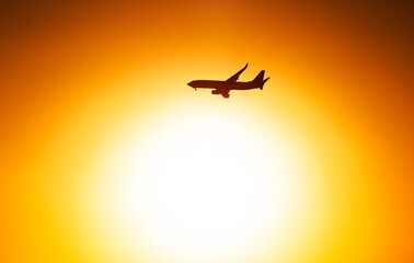 Airplane silhouette against sunrise sky. Aviation industry concept image with orange sky background.
