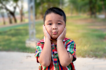 Fototapeta premium Asian little boy covering his ears while noisy environment