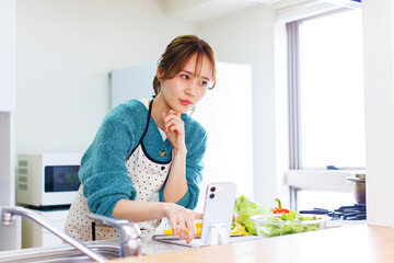 日本人女性は料理の準備をしながら電話でレシピを参照してください