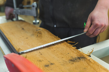 closeup shot of carpenter measuring a wooden piece with a tape measure, working on wood. High quality photo