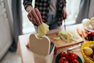 The cook throwing food peels in a compost bin for fermentation. Female person recycling organic...