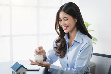 Businesswoman holding a house model House on Hand with piggy bank.Real estate,Property insurance and security concept.Savings and finance concept.