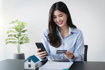 Woman using credit card and mobile phone for online shopping purchasing, buying at home, paying bills from home.