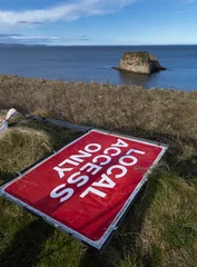 Foto op Plexiglas Fallen road sign. Local access only. Cliffs and bay at Dunnet Head. Scotland. North coast. North Sea. Orkney Islands in the back. © A