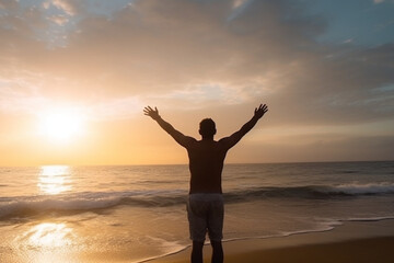Fototapeta na wymiar back view of Young man arms outstretched by the sea at sunrise enjoying freedom and life