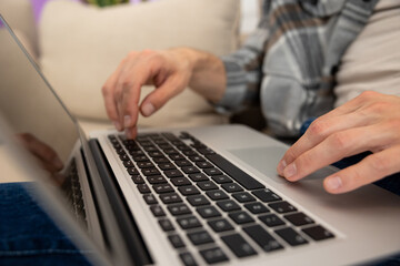 Unrecognizable guy using laptop working online typing keyboard.