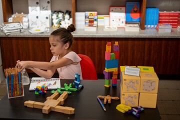 preschool female child playing with educational toy blocks and colors