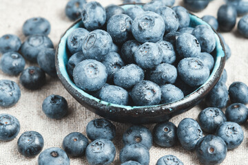 Blueberries with water drops in a ceramic bowl and scattered around.