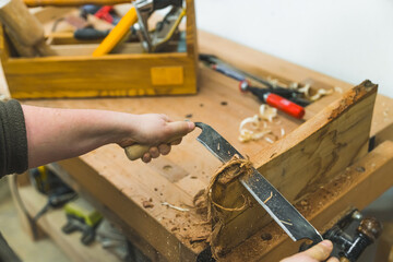 Carpenter using draw shave tool to smooth out the wood in a carpenter workshop. High quality photo