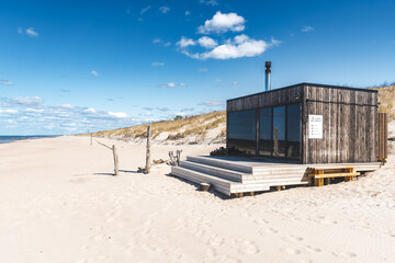 Obraz na płótnie Canvas Beautiful modern wooden sauna on a white sandy beach for renting with view on the Baltic Sea and cloudy sky in Palanga, Klaipeda, Lithuania