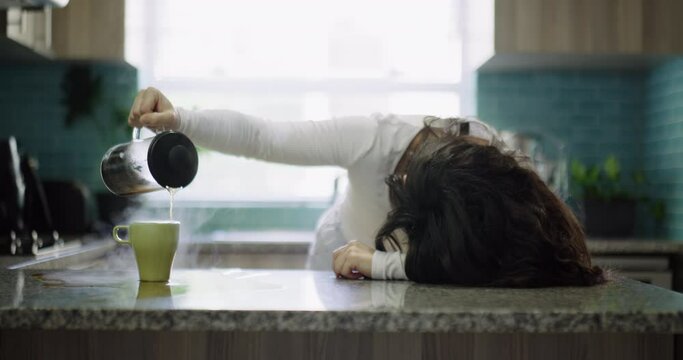 Woman, tired and pouring coffee in a home kitchen for morning energy while frustrated or depressed. Sad female person with a tea cup and press on counter with mess, stress and mental health problem