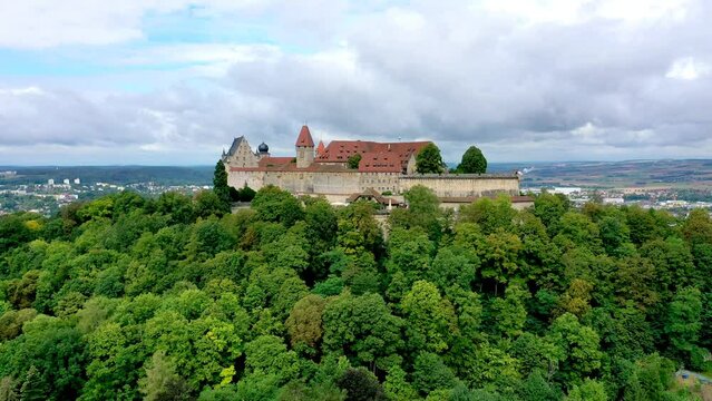 Aerial pedestal up footage view of the castle Coburg with forest flying up, Germany