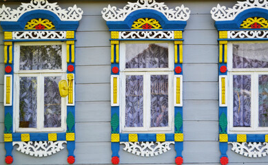 Fototapeta na wymiar Three wooden windows with carved multi-colored antique frames.