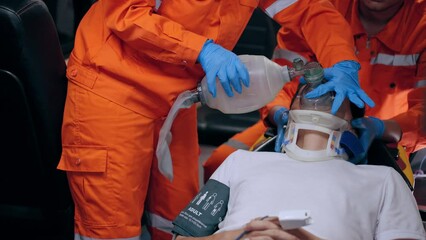 Asian emergency medical technician (EMT) or paramedic giving emergency oxygen with patient in ambulance car