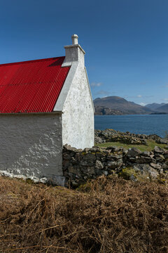 Loch Claira Scottish Highlands. Scotland. Lake.  Little white cottage with red roof. Mountains. Wall of rocks. 