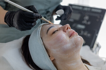Woman in a spa salon on cosmetic procedures for facial care. Cosmetologist making a woman a...