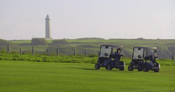 Golf cars stand on a green golf course on the shores of the Atlantic ocean in France