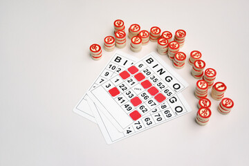 Many wooden chips with numbers and cards for a board game of bingo or lotto on a light background.