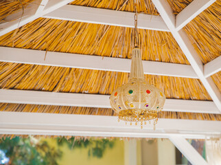 Close up view of a traditional bamboo lampshade hanging on the roof of the garden gazebo