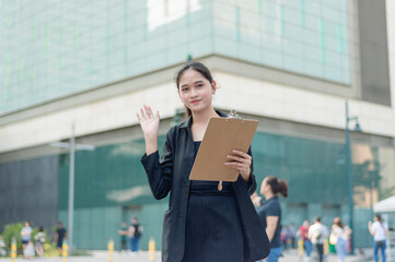A lovely lady standing outside, in the city wearing a black suit, and black skirt saying 'hi' at...
