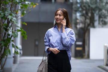 仕事に出かけながら電話で話している日本人女性