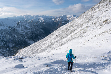 Fototapeta na wymiar Adventurous women hiker on top of a steep rocky cliff overlooking winter alpine like moutain landscape of High Tatras, Slovakia.