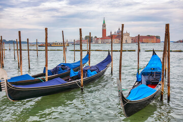 Fototapeta na wymiar Captivating landscape with Church of San Giorgio Maggiore on background and gondolas parked beside the Riva degli Schiavoni in Venice