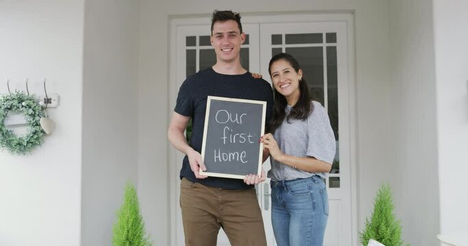Portrait, property and a homeowner couple with a chalkboard for an announcement of their purchase together. Love, happy or smile with a man and woman looking proud of their real estate investment