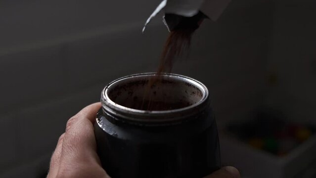 fill the coffee pot with moka, close-up against light in the morning to start the day
