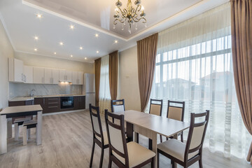 Elegant interior design of the kitchen and dining room in a luxurious mansion. Windows with beautiful curtains. Stylish furniture.