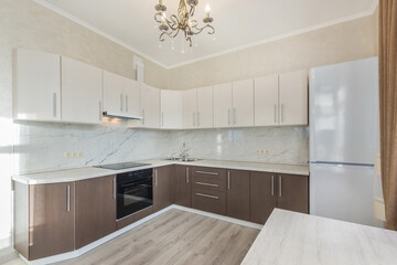 Kitchen set of contrasting colors with built-in appliances in the interior of a modern kitchen. Beautiful chandelier.