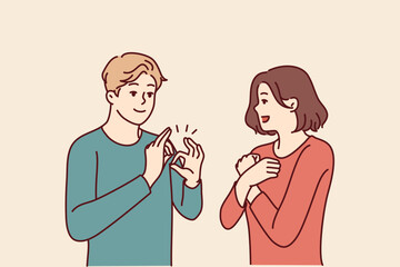 Fototapeta premium Deaf-mute man and woman are talking using sign language and demonstrating symbols with hands. Guy teaches girl sign language for concept of inclusiveness and socialization of people with disabilities