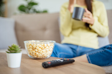 Asian woman Watching smart TV and using remote controller Hand holding television audio remote control at home with the remote control television